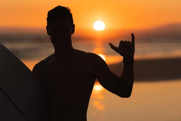 Schwarze Silhouette Eines Athletischen Surfers Der Shaka Bei Sonnenuntergang Zeigt — Stockfoto