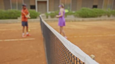 Tenis maçından önce ağda duran bulanık adam ve kadın. Orta çekim