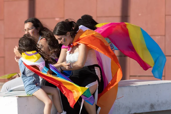 Lizbon, Portekiz - 24 Haziran 2023 - Terreiro do Paco Praca do Comercio: Festivalde sırtında gurur bayrakları olan genç eşcinsel insanlar. Orta çekim