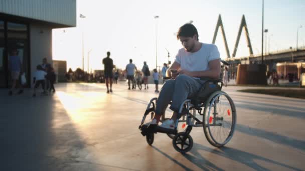 Mężczyzna Wózku Inwalidzkim Sprawdza Telefon Potem Patrzy Kamerę Macha Ręką — Wideo stockowe