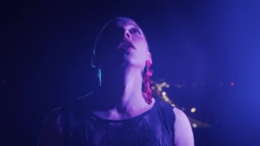 Mavi ışıkta duran kısa saçlı bir travesti. Portre