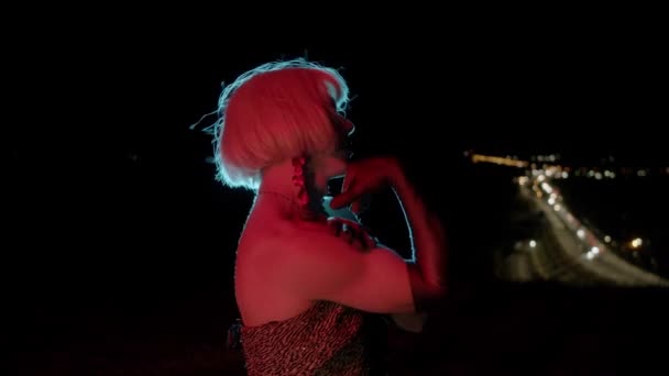 穿着金色假发的拖曳女王在夜间的红色灯光下在摄像机前炫耀 肖像画 — 图库视频影像