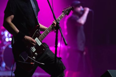 Gitarist parlak ışıklarla sahneye çıkıyor. Orta çekim