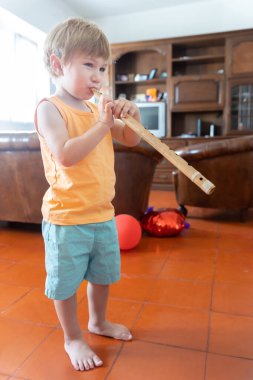 Küçük çocuk evde flüt çalıyor. Dikey çekim