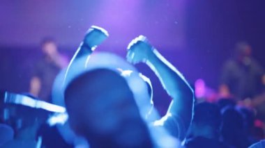 İnsanlar gece kulübündeki konserlerden hoşlanırlar. Bir adam tempo tutarak zıplar. Orta çekim