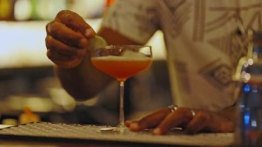 Barmen alkollü içeceği bir dilim limonla süslüyor. Orta çekim