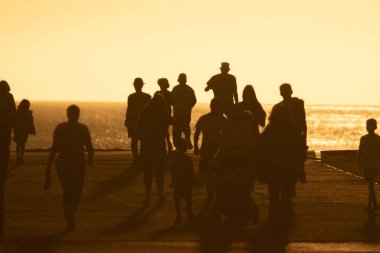 Sarı, parlak günbatımında yürüyen insanların siluetleri. Orta çekim