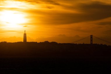 Uzakta parlak turuncu günbatımında İsa 'nın heykeli. Orta çekim