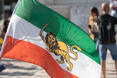 Elinde bir Aslan ile İran bayrağı tutan biri. Orta çekim