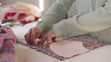 Kadın tasarımcı çiçek desenli kumaşta kağıt desenler kullanarak iz bırakıyor. Orta çekim
