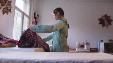 Bir terzi atölyede çiçek dokusunu düzleştirir. Orta çekim