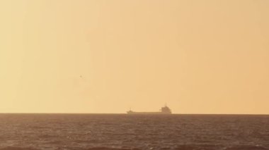 Günbatımı gökyüzünün arka planına karşı sanayi gemisi denizde ilerliyor. Orta çekim