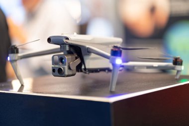Quadcopter drone havada süzülüyor, mavi LED ışıklar gösteriyor.