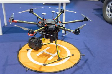 Gelişmiş çoklu-rotor drone mavi arkaplanlı bir platformda görüntülendi.
