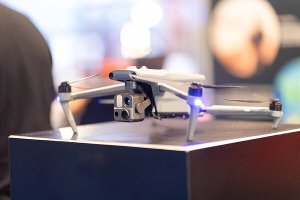 Flying drone with brightly lit propellers against a blurred background.