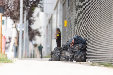 Terk edilmiş çantalar ve çöp yığını desenli bir sokak duvarının yanında. Garbej.