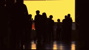Bir sürü insan altın sarısı bir ışıkla siluete bürünmüş - tanınmayan insanlar - havaalanı ya da konferans, sarı