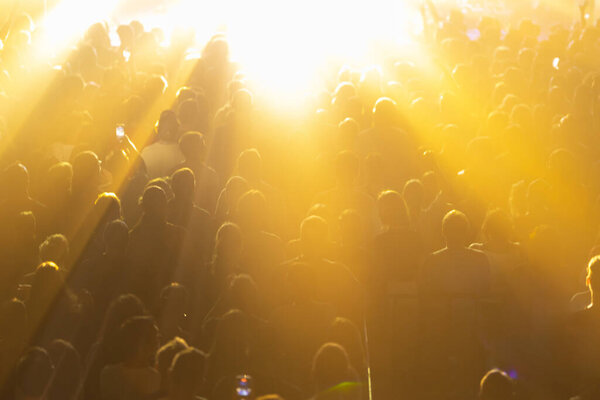 A lively concert scene where the crowd is bathed in brilliant yellow lights.