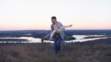 Tepede küçük bir kızı tutan bir adam.