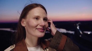 Arka planda gün batımında poz veren bir kadın