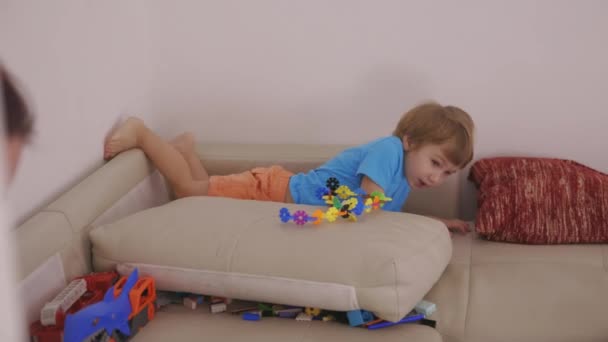 一个小男孩躺在沙发上拿着玩具 — 图库视频影像