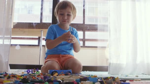 Ein Kleiner Junge Sitzt Auf Dem Boden Umgeben Von Spielzeug — Stockvideo