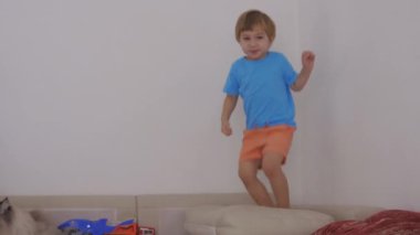 Genç bir çocuk yatakta zıplıyor.