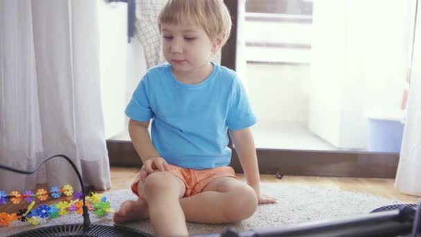 Ένα Μικρό Αγόρι Κάθεται Στο Πάτωμα Και Παίζει Παιχνίδια — Αρχείο Βίντεο