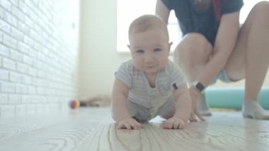 Annesinin bakışlarıyla yerde sürünen küçük bir bebek. Orta çekim