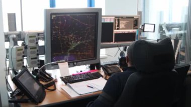 Havaalanındaki seyir kontrol odası. Haritada uçuş yolları olan bir monitörle çalışan bir adam. Orta çekim