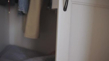 Çocukluk oyunları. Küçük çocuk büyük elbise dolabında saklambaç oynuyor.