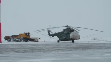 Havaalanı pistinin tepesinde oturan bir helikopter.