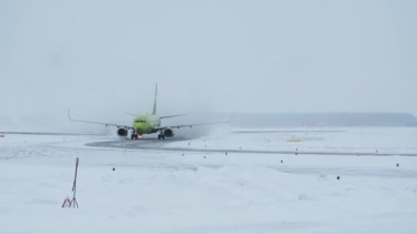 Kışın havaalanındaki karlı havaalanında hareket eden yolcu uçağı, telefonla vuruldu.