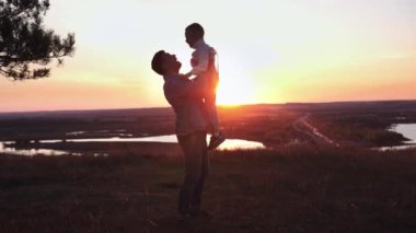 Oğlunu güzel bir gün batımında atan bir adam, telefoto.