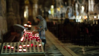 Katolik kilisesinde mumlarla dolu bir kadın var.