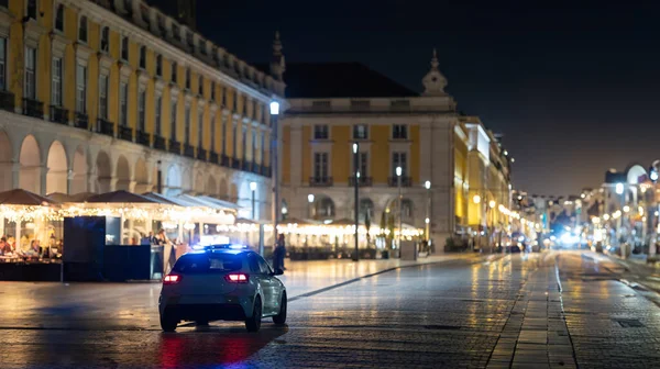 A police car driving down a street at night - telephoto