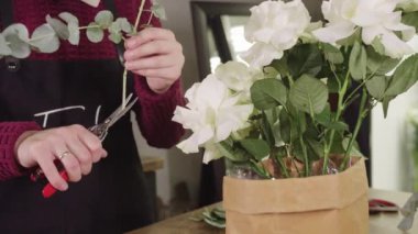 Bir makasla çiçek kesen bir kadın.