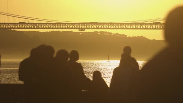 水の体の隣に座っている人々のグループ 黄金の日没 — ストック動画
