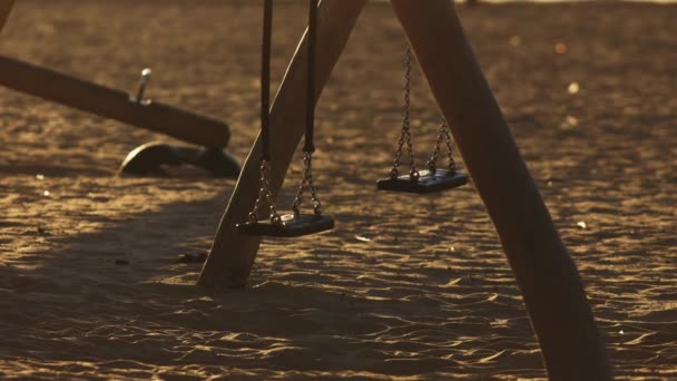 日没の砂の子供のための空のスイングセット — ストック動画