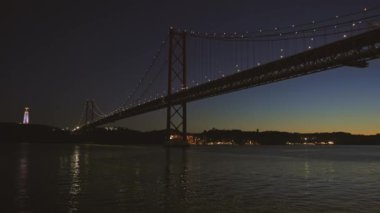 Geceleri bir su kütlesinin üzerinde büyük bir köprü.