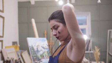 Sanat stüdyosunda kolunu kaldıran bir kadın.