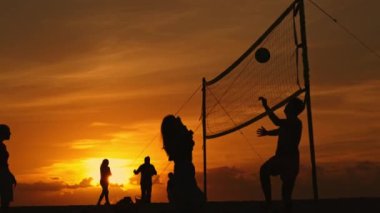 Gün batımında voleybol oynayan bir grup insan