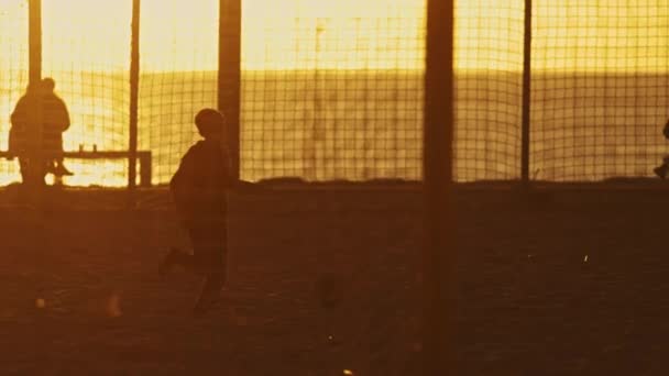 日没の海岸でサッカーのゲームをしている10代の子供 — ストック動画