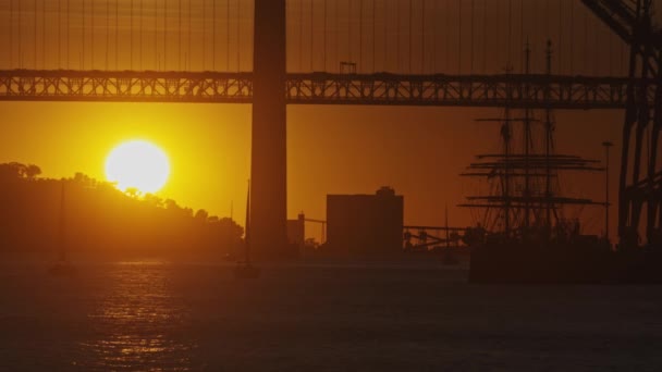 Słońce Zachodzi Mostem Nad Akwenem Przed Żaglowcem — Wideo stockowe