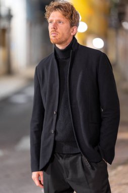 Gece sokakta siyah takım elbiseli yakışıklı bir adam - dikey