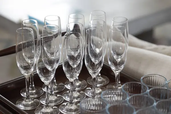 A tray of glasses with a variety of shapes and sizes. The glasses are arranged in a neat and orderly fashion, with some standing upright and others sitting on their sides