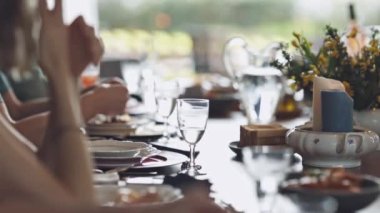 Bir grup insan bir tabak yemek ve bir bardak suyla bir masada oturuyor. Masa, bir kase çorba ve bir tabak makarna da dahil olmak üzere çeşitli yemeklerle hazırlandı. Atmosfer sıradan.
