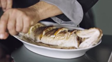 Bir adam şef restoranda kızarmış balık kesiyor. Yakın plan.