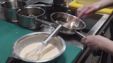 Bir insan yoğun bir bar ortamında çırpıcı kullanarak bir kase malzemeyi hararetle karıştırır..