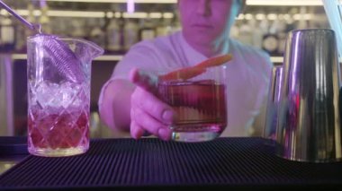Barda barmen portakal suyuyla içki yapıyor, çeşitli malzemeler ve bar aletleri kullanarak ustalıkla lezzetli bir içecek yapıyor..